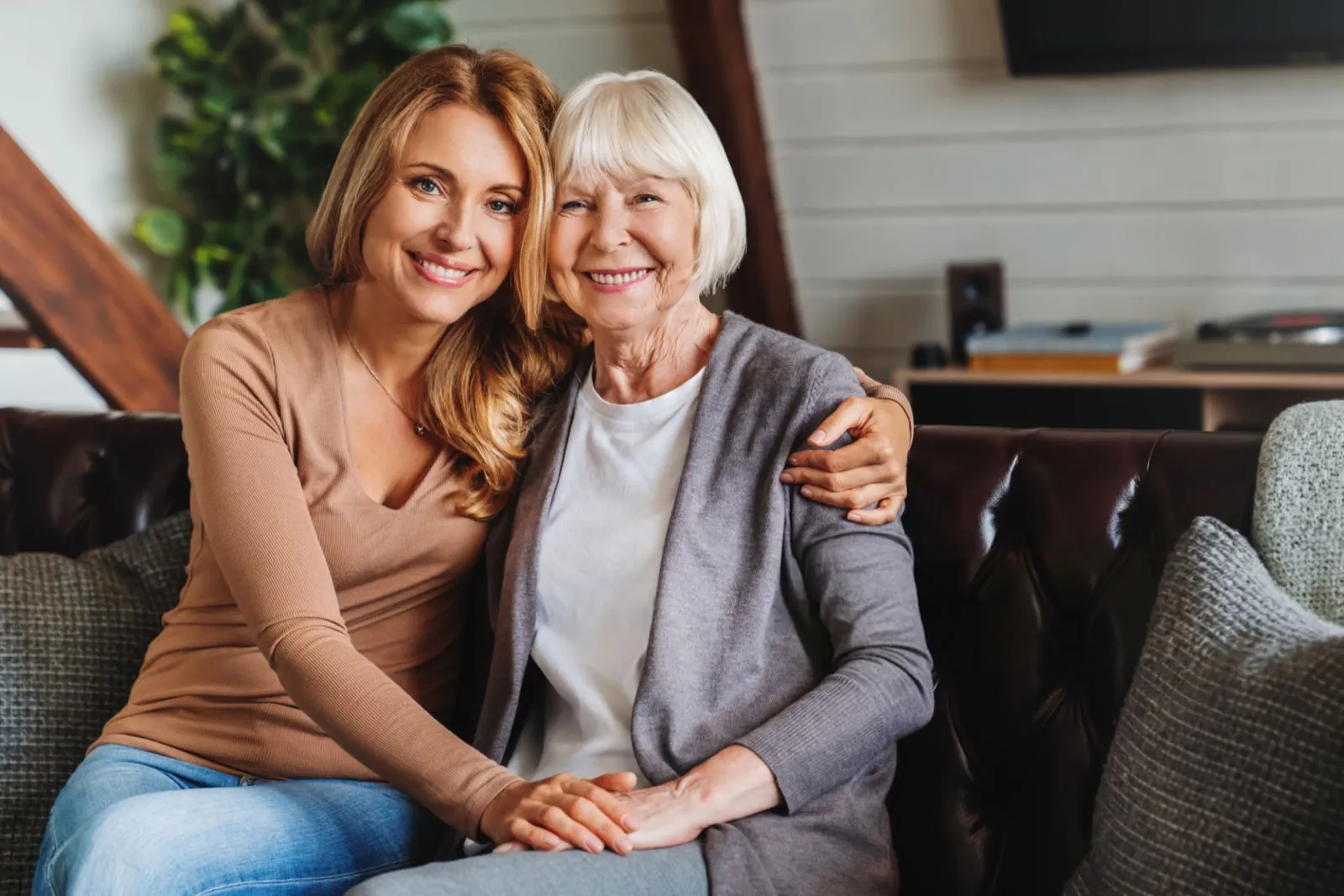 A Goldy Enrichment Specialist and an older woman smiling together on a couch at home