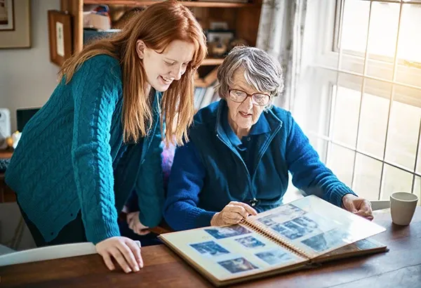 Two women looking at old photo albums together by a window