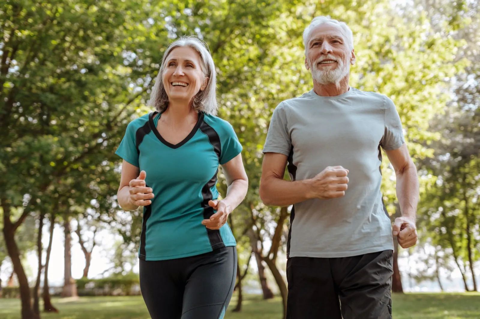 An active older couple jogging together in a sunny park