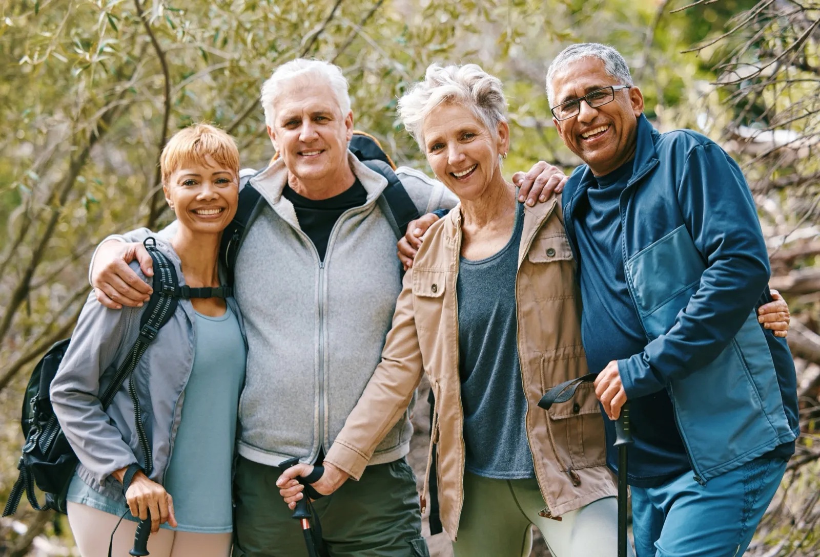 Four older friends hiking together on a wooded trail
