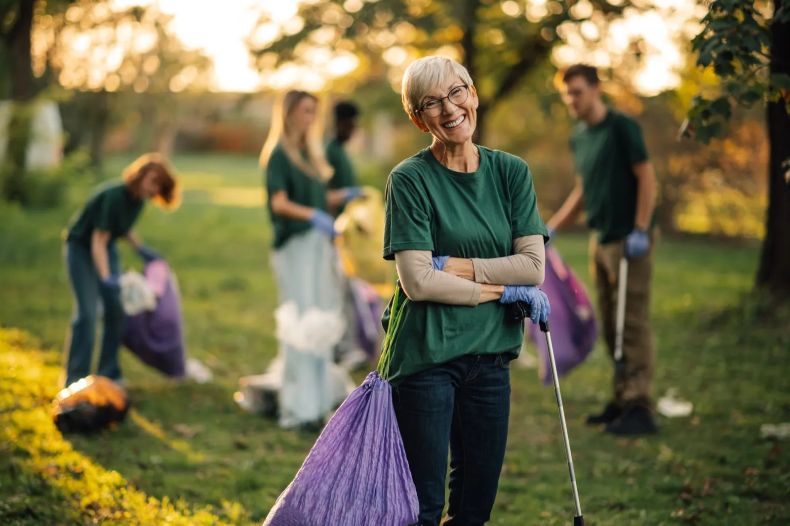 An older woman smiling while volunteering at a park cleanup