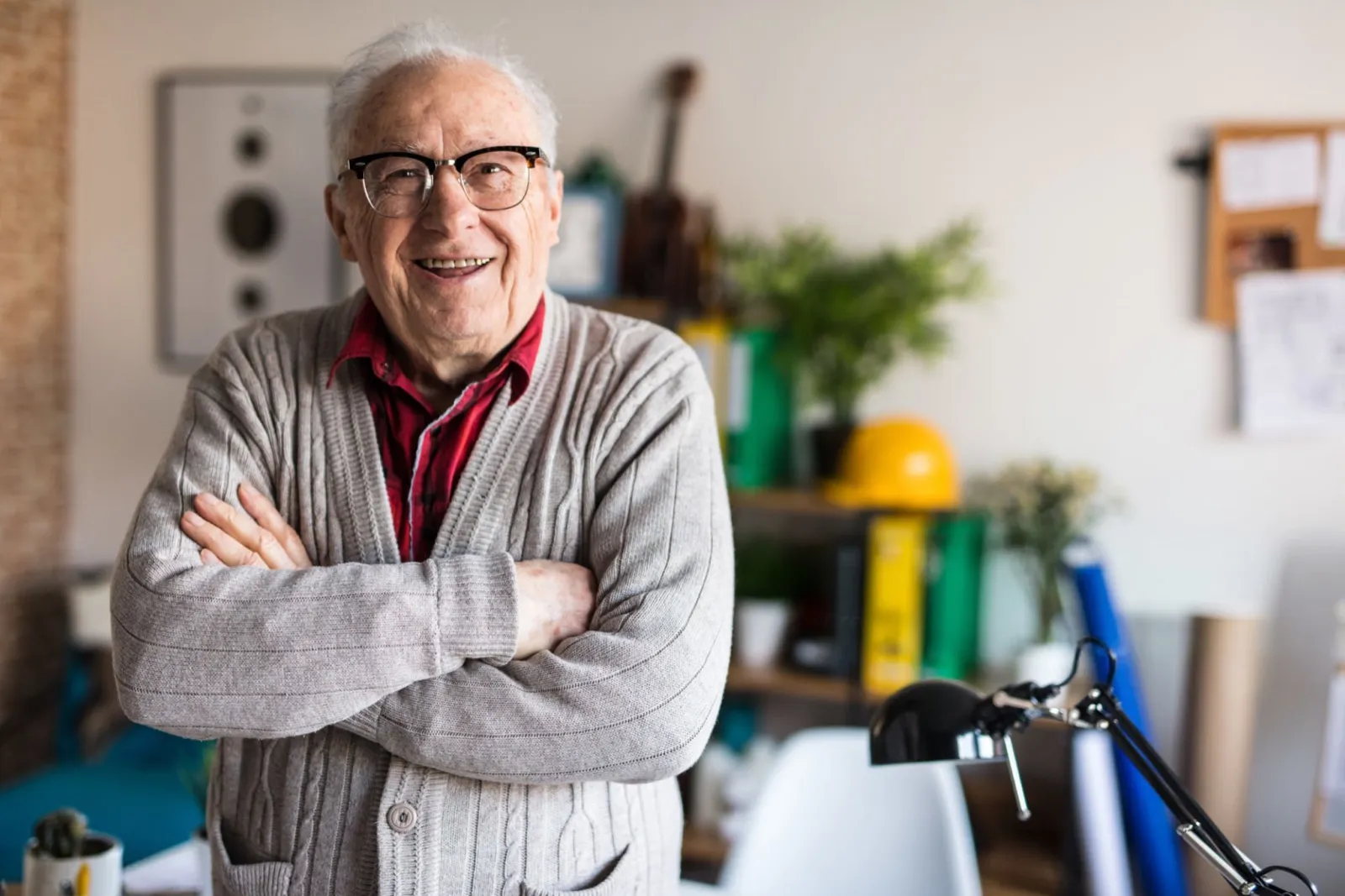 A smiling older man with his arms crossed at home