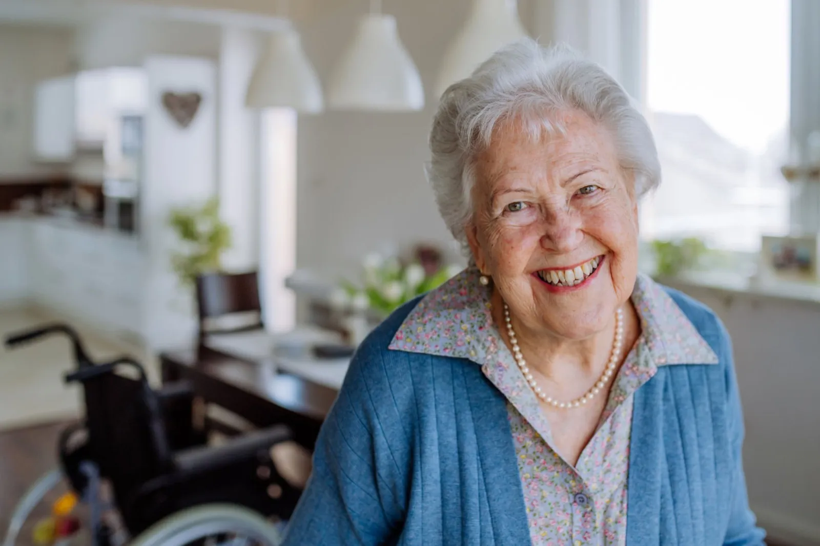 A smiling older woman wearing a pearl necklace at home