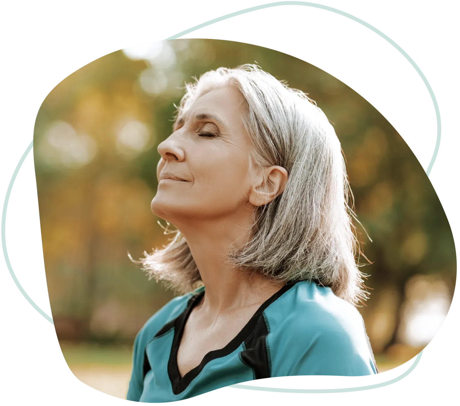 An older woman taking a deep breath outdoors with her eyes closed