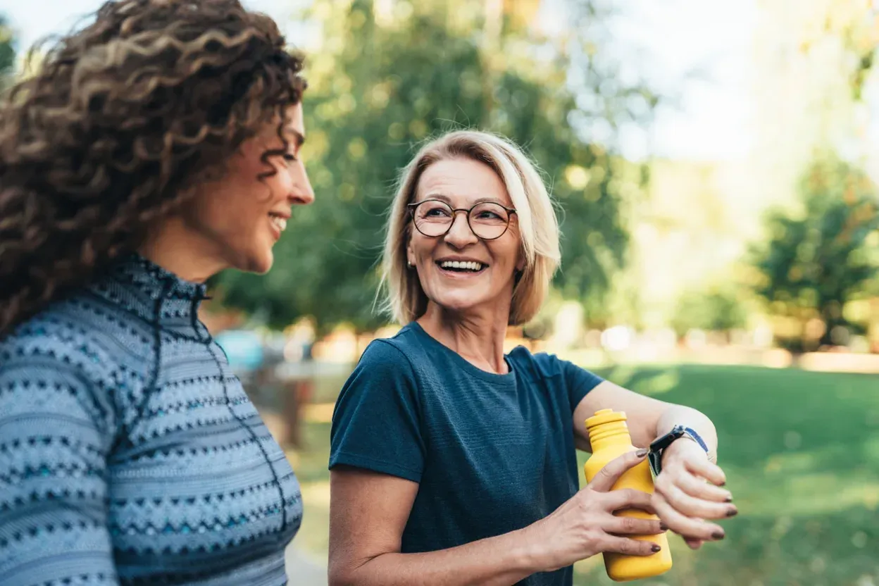 An older woman laughing with a companion while out walking in a park